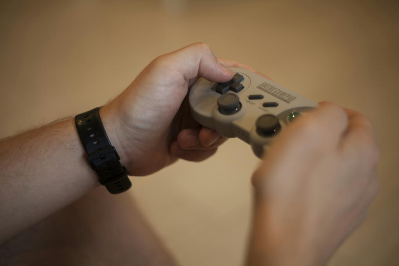 Orang yang memegang pengontrol game Xbox One putih dan hitam